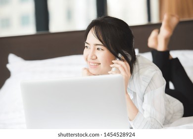 Happy Asian Business Woman Talking With Cell Phone Laying Down On The Bed.