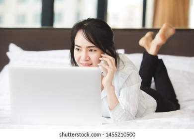 Happy Asian Business Woman Talking With Cell Phone Laying Down On The Bed.