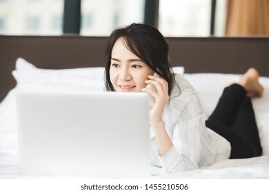 Happy Asian Business Woman Talking With Cell Phone Laying Down On The Bed.