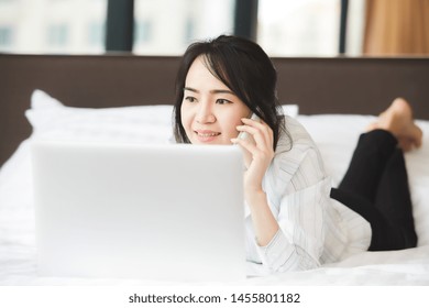 Happy Asian Business Woman Talking With Cell Phone Laying Down On The Bed.