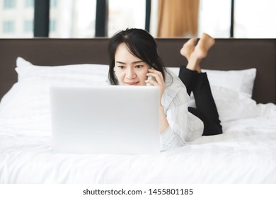 Happy Asian Business Woman Talking With Cell Phone Laying Down On The Bed.