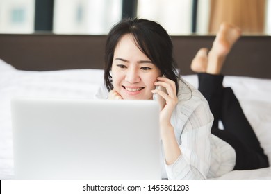 Happy Asian Business Woman Talking With Cell Phone Laying Down On The Bed.