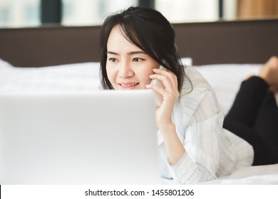 Happy Asian Business Woman Talking With Cell Phone Laying Down On The Bed.