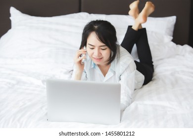 Happy Asian Business Woman Talking With Cell Phone Laying Down On The Bed.