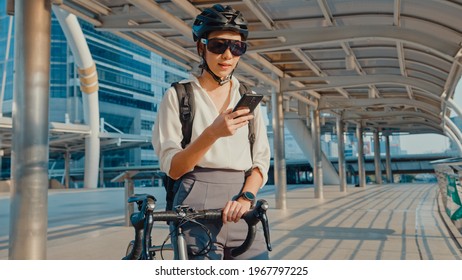 Happy asian businesswoman with backpack use smart phone in city stand at street with bike go to work at office. Sport girl use her phone for working job. Commute to work, Business commuter in city. - Powered by Shutterstock