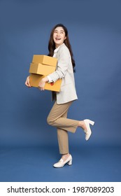 Happy Asian businesswoman holding package parcel box isolated on blue background, Delivery courier and shipping service and full body composition concept