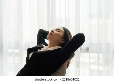 Happy Asian Businesswoman Sit On Chair At Workplace Enjoy Ending Of Workday, Relaxed Posture Hands Behind Head Feels Satisfied With Work Done. Tired Woman Sleeping At Her Chair In Office, Overworked