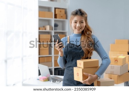 Happy Asian businesswoman starting sme holding smartphone. Small Online Business Owner, SME Work From Home Box, SME Online Marketing and Product Packing and Delivery Service.