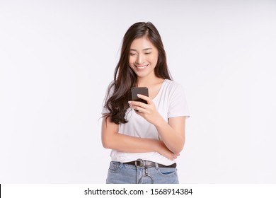 Happy Asian Businesswoman Using Mobile Phone Isolated Over White Background. Girl Holding The Smartphone In A Summer T-shirt Short Jeans. Copy Space 