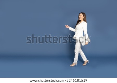 Happy Asian businesswoman walking and holding laptop computer over blue background Stock photo © 