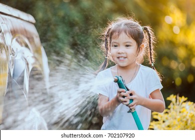 Happy asian child girl help parent washing car on water splashing with sunlight - Powered by Shutterstock