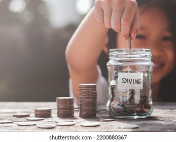 Happy Asian Child Girl Save Money By Putting Coins In Glass Jar, Coin Stack Growing. Concept Saving Money, Cash, Education, Growth, Finance, Bank, Investment, Management, Income, Business