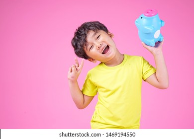 Happy Asian Child Holding Pink Piggy Bank, Isolated On Pink Background