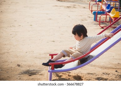 Happy Asian Child On Slide At Playground