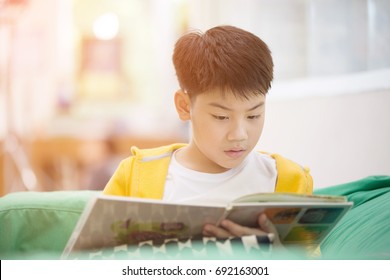 Happy Asian Child Reading Book With Smile Face. With Sun Light In Morning At Home