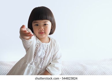 Happy Asian Child Sitting On Bed With White Background