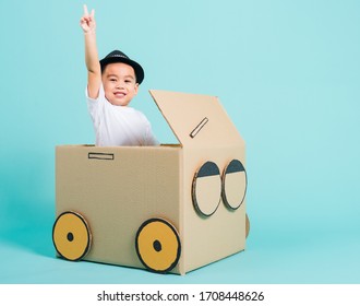 Happy Asian Children Boy Smile In Driving Play Car Creative By A Cardboard Box Imagination, Summer Holiday Travel Concept, Studio Shot On Blue Background With Copy Space For Text