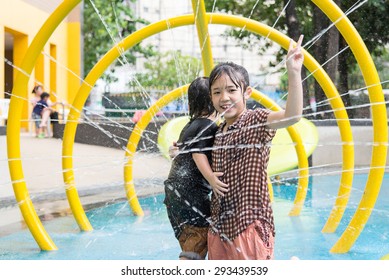 Happy Asian Children Has Fun Playing In Water Fountains In Water Park