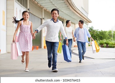 Happy Asian Children And Parents Running With Shopping Bags