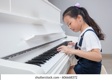 Happy Asian Chinese little girl playing classical piano in the living room at home
