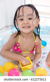 Happy Asian Chinese Little Girl Playing In The Inflatable Pool Inside The House.