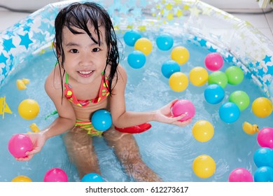 Happy Asian Chinese Little Girl Playing In The Inflatable Pool Inside The House.