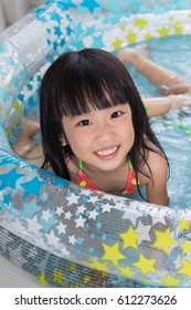 Happy Asian Chinese Little Girl Playing In The Inflatable Pool Inside The House.