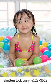 Happy Asian Chinese Little Girl Playing In The Inflatable Pool Inside The House.