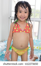 Happy Asian Chinese Little Girl Playing In The Inflatable Pool Inside The House.