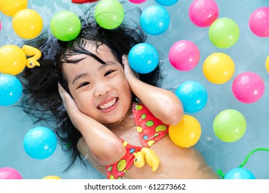 Happy Asian Chinese Little Girl Playing In The Inflatable Pool Inside The House.