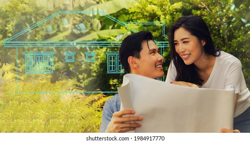 Happy Asian Couple Admires The Blueprints Of The Beautifully Designed Houses. There Is Excitement, Satisfaction And Delight In Getting A New Home Built On Their Land.