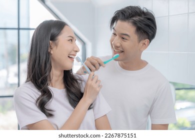 Happy Asian couple brushing their teeth together in the bathroom. - Powered by Shutterstock