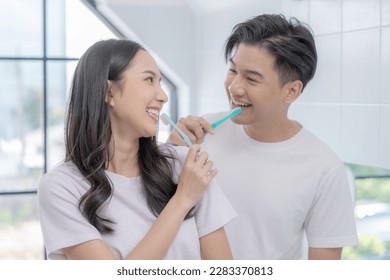 Happy Asian couple brushing their teeth in the bathroom in the morning.