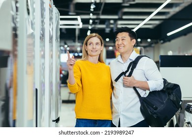 Happy Asian Couple Family Man And Woman Make A Choice Choose Of New Household Home Appliances In Supermarket Survey Refrigerator Fridge Cooler, Freezer, Cold Store Purchase And Shopping