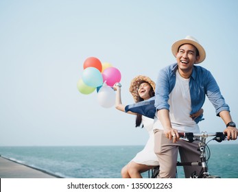 Happy Asian Couple Lover Cycling Together On The Beach.