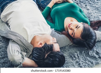 Schönes asiatisches Paar, das auf dem Wohnzimmerboden zusammen auf Teppich liegt. Liebe Beziehung und Lifestyle Konzept.
