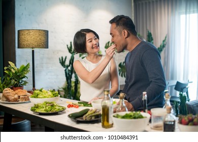 Happy Asian couple preparing food in the kitchen at home.