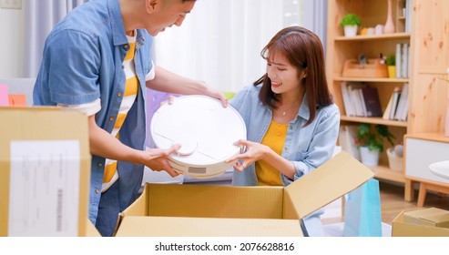 Happy Asian Couple Receive Packing Parcel After Online Shopping At Home And There Is A New Robot Vacuum Cleaner In Opening Delivery Box