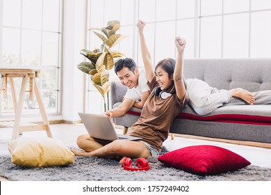 Happy Asian couple shopping online with laptop computer at home. Lovely couple making purchases online or booking in beautiful living room. Buying ordering products on the internet. - Powered by Shutterstock