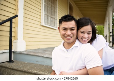 A Happy Asian Couple Sitting On The Porch In Front Of Their House