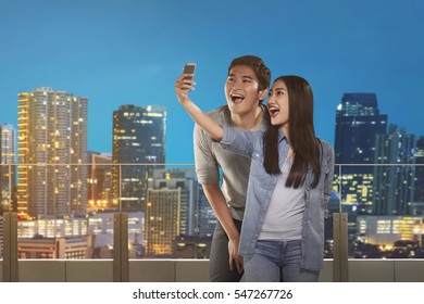 Happy asian couple taking selfie in the roof terrace
