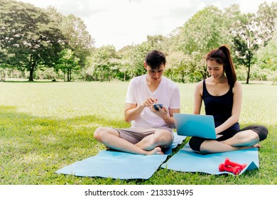 Happy Asian Couple Using Laptop Typing Keyboard To Order Online Gym Equipment After Gym Activity In Young Woman Using Online Connection Smartphone Hotspot For Convenience.