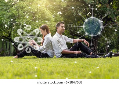 Happy Asian Couple Using And Listening The Song And Using The Social Network Via Smart Mobile Phone For Online Shopping With Omni Channel In The Park, Lifestyle And Technology Concept