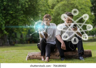 Happy Asian Couple Using And Listening The Song And Using The Social Network Via Smart Mobile Phone For Online Shopping With Omni Channel In The Park, Lifestyle And Technology Concept