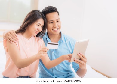 Happy Asian Couple Using Tablet And Credit Card For Online Shopping