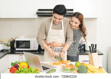 Happy Asian Couple Watching Tv Show On The Laptop And Cooking Dinner