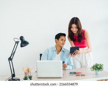 Happy Asian Couple, Young Man And Woman Using Tablet And Laptop Computer Together For Flight Booking, Hotel Room And Trip Information At Home, Ready To Travel, Happy Holiday, Summer Vacation Concept.