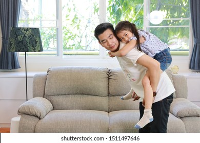 Happy Asian Dad Holding His Daughter While He Standing In Living Room With Smiling Face (lifestyle Concept)