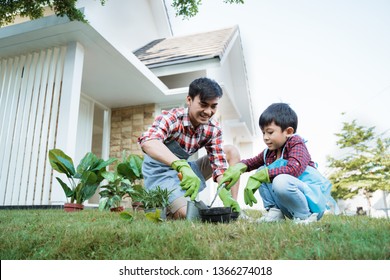 Happy Asian Daddy And Son Gardening At His House Garden Together Planting New Tree