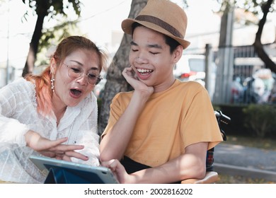 Happy Asian Disabled Teen Boy On Wheelchair Using Digital Tablet Making Video Call With His Mother Help, Lifestyle In Education Of Disabled Kid, Remote Learning And Homeschooling Concept.